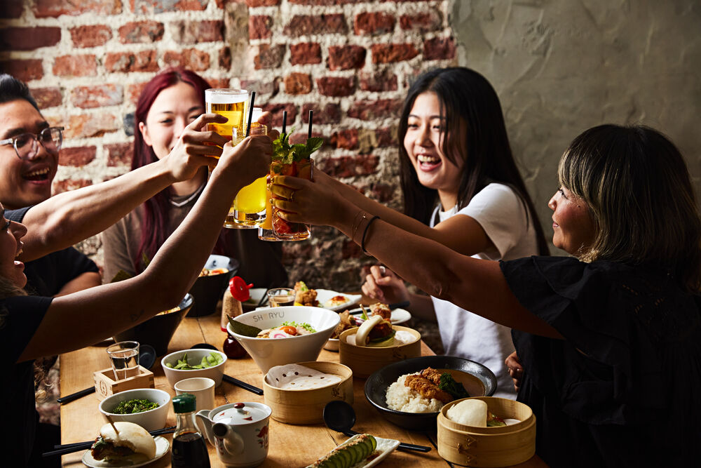 Friends raising a toast over dinner at Shoryu Soho
